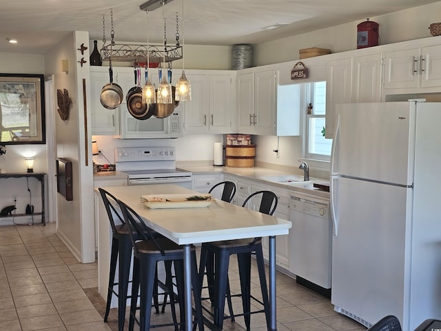 kitchen featuring sink, white appliances, a kitchen breakfast bar, and white cabinets