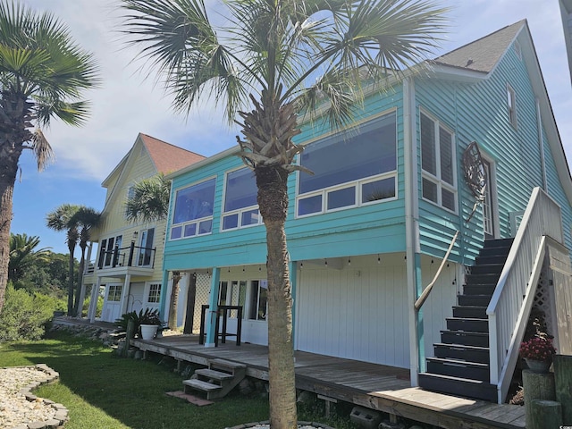 rear view of property featuring a balcony and a yard