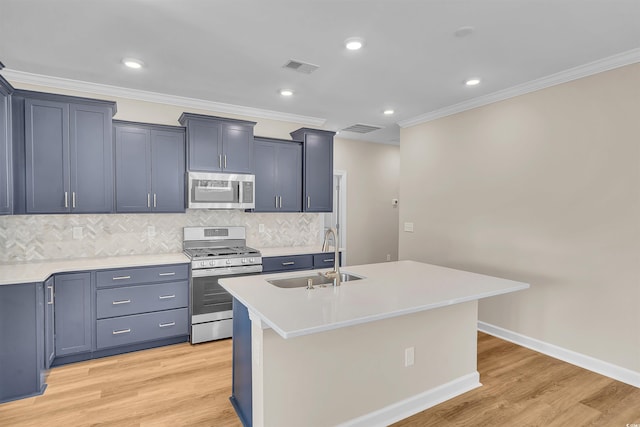 kitchen with a kitchen island with sink, light wood-type flooring, sink, and appliances with stainless steel finishes