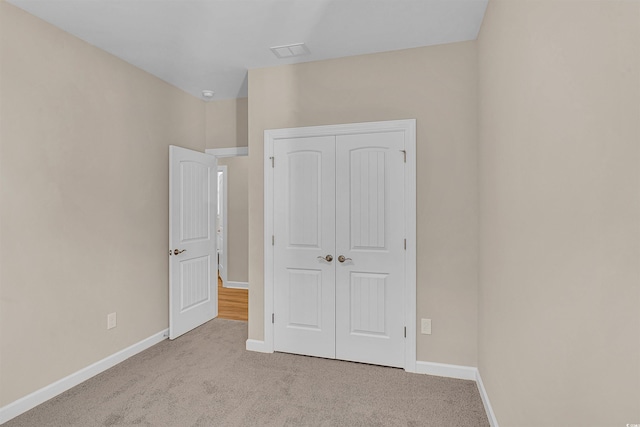 unfurnished bedroom featuring light colored carpet and a closet