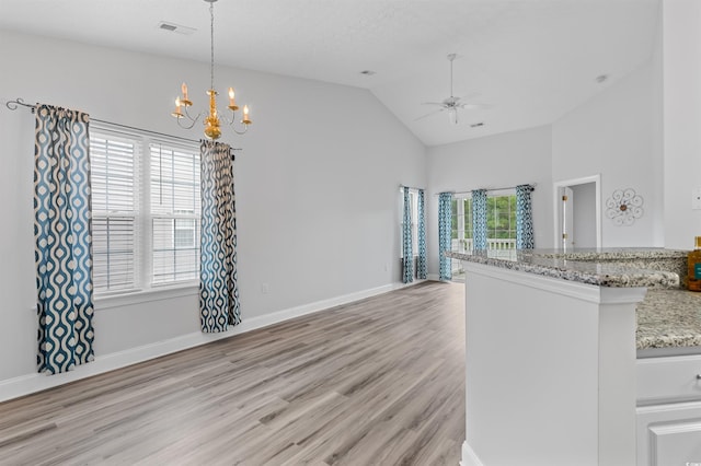 kitchen with light stone countertops, lofted ceiling, decorative light fixtures, ceiling fan with notable chandelier, and light wood-type flooring