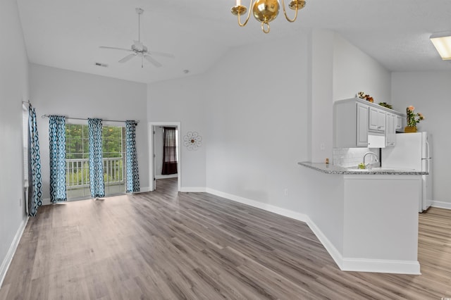 unfurnished living room featuring light hardwood / wood-style flooring, high vaulted ceiling, ceiling fan with notable chandelier, and sink