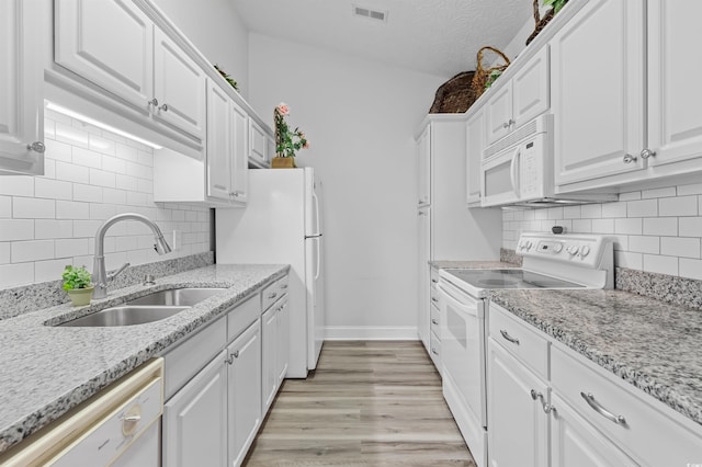 kitchen with white cabinets, light stone countertops, white appliances, and sink