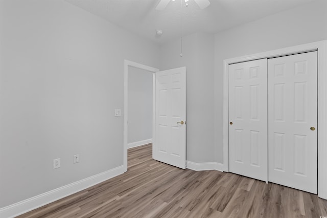 unfurnished bedroom featuring ceiling fan, light wood-type flooring, and a closet