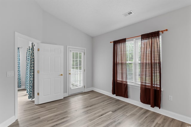 spare room with plenty of natural light, light hardwood / wood-style floors, and vaulted ceiling