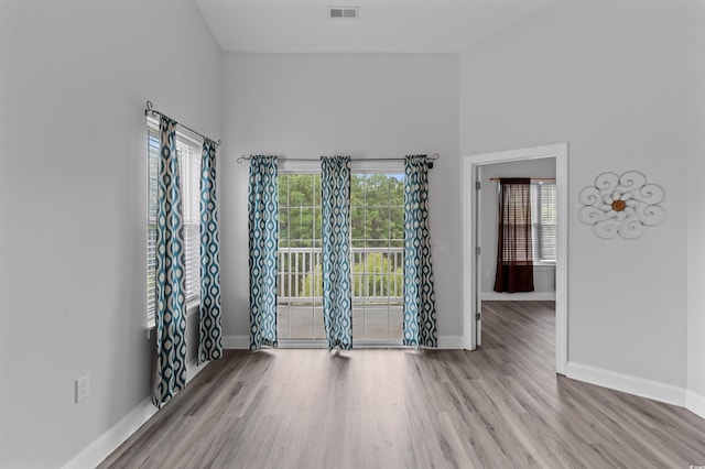 spare room with light hardwood / wood-style floors and a towering ceiling