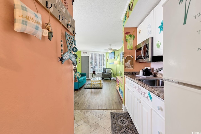 7000 Ocean Blvd N Unit 133, Myrtle Beach, SC 29572 - kitchen featuring freestanding refrigerator, stainless steel microwave, white cabinetry, a ceiling fan, and a textured ceiling