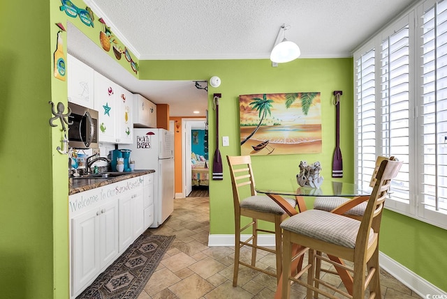 kitchen featuring white cabinetry, sink, white refrigerator, and ornamental molding