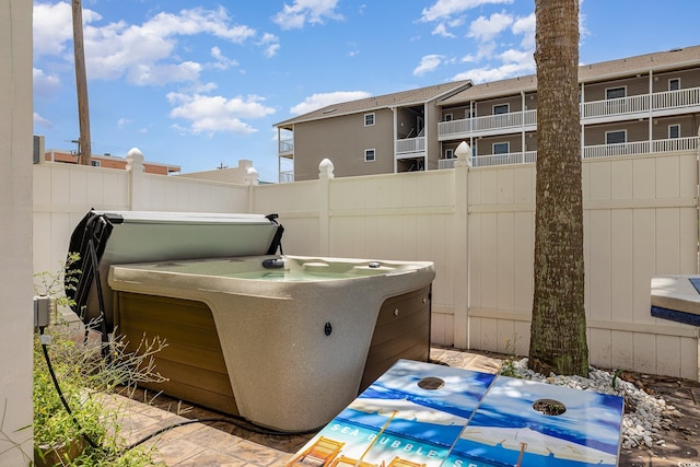 view of patio with a balcony and a hot tub