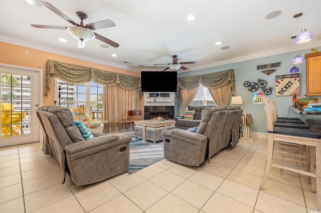 tiled living room with a large fireplace, ornamental molding, and ceiling fan