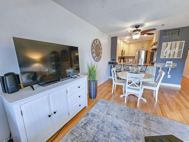 dining area with ceiling fan, a textured ceiling, and light hardwood / wood-style floors