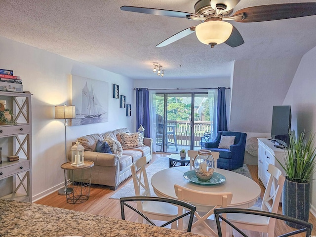 living room with a textured ceiling, ceiling fan, and light hardwood / wood-style flooring