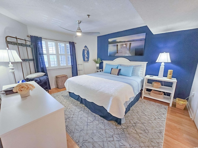 bedroom featuring light wood-type flooring, a textured ceiling, and ceiling fan