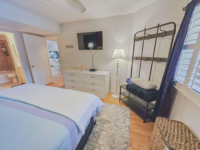 bedroom with light hardwood / wood-style floors, connected bathroom, ceiling fan, and multiple windows