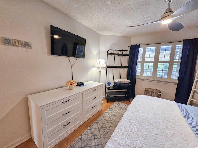 bedroom with a textured ceiling, ceiling fan, and light hardwood / wood-style flooring