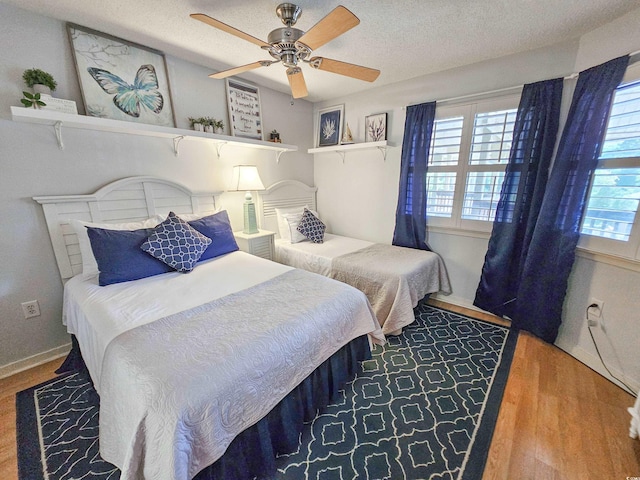 bedroom with wood-type flooring, multiple windows, ceiling fan, and a textured ceiling