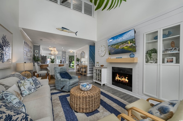 living room featuring hardwood / wood-style flooring, a fireplace, built in features, and a high ceiling