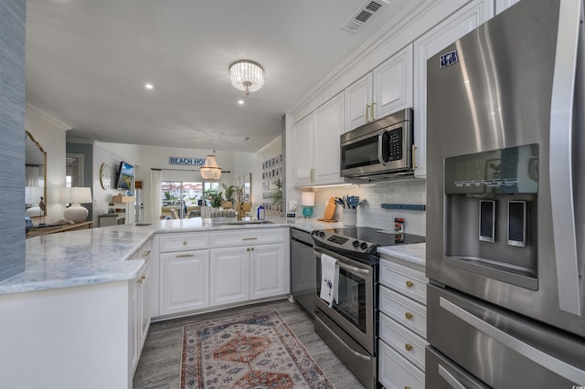 kitchen featuring sink, white cabinetry, stainless steel appliances, tasteful backsplash, and kitchen peninsula