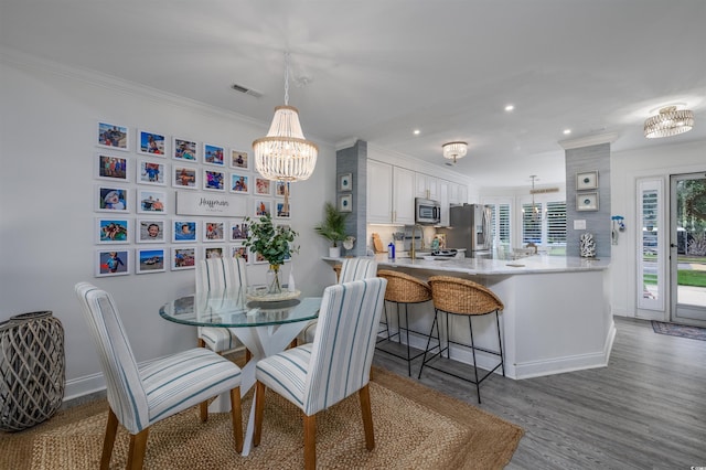 dining space with dark hardwood / wood-style flooring, sink, crown molding, and an inviting chandelier