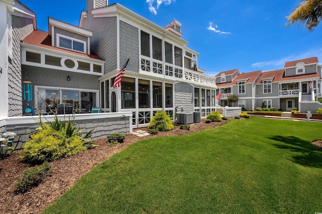 rear view of property with a yard, central AC unit, and a sunroom