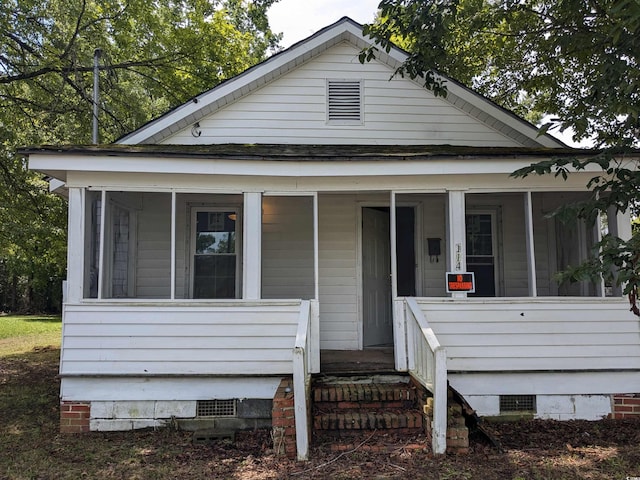 view of front facade featuring crawl space, covered porch, and a shingled roof