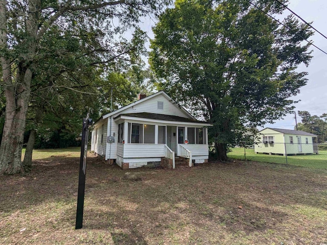 view of front facade with a porch, a front yard, crawl space, and fence