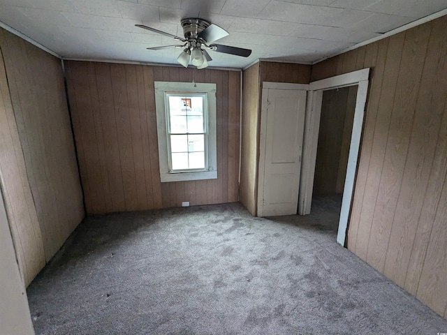 empty room featuring light carpet, ceiling fan, and wooden walls