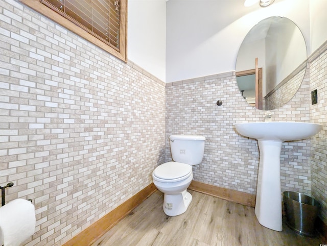 bathroom with toilet, hardwood / wood-style floors, and tile walls