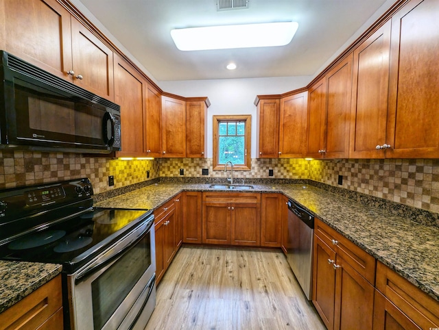 kitchen with sink, light hardwood / wood-style flooring, dark stone countertops, and stainless steel appliances