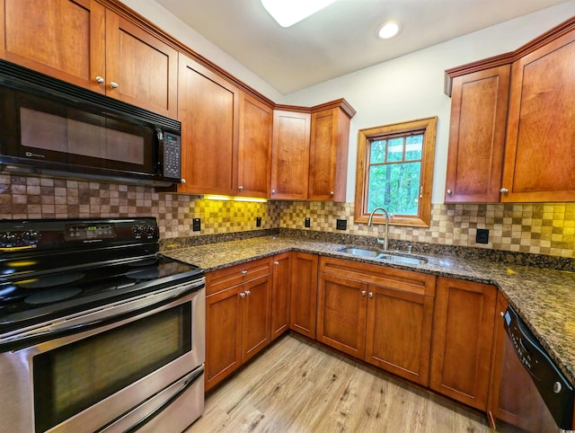 kitchen featuring stainless steel appliances, dark stone countertops, decorative backsplash, sink, and light hardwood / wood-style flooring