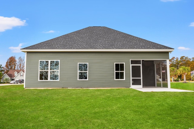 rear view of house with a sunroom, a shingled roof, and a yard