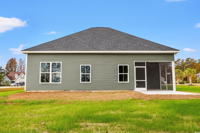 back of house featuring a shingled roof, a sunroom, and a lawn