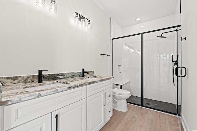 full bath featuring a sink, a shower stall, toilet, and wood finished floors