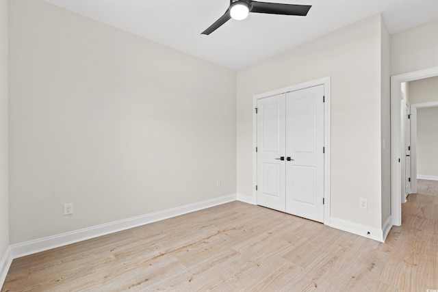 unfurnished bedroom with a ceiling fan, a closet, light wood-style flooring, and baseboards