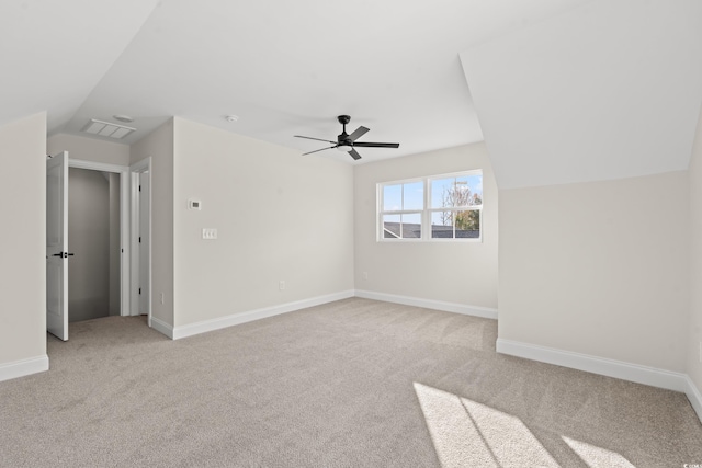 unfurnished room with light colored carpet, a ceiling fan, baseboards, vaulted ceiling, and visible vents