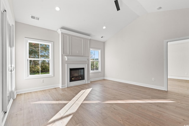 unfurnished living room featuring lofted ceiling, visible vents, a large fireplace, light wood-type flooring, and baseboards