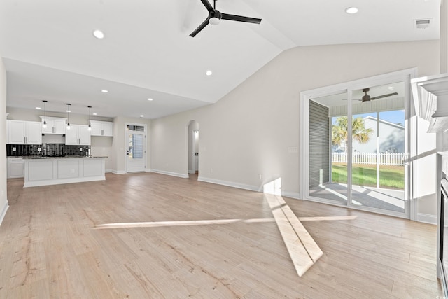 unfurnished living room featuring arched walkways, a ceiling fan, and light wood-style floors