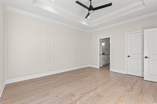 unfurnished bedroom featuring light wood-style floors, a tray ceiling, and a decorative wall