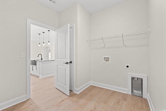 laundry area with baseboards, arched walkways, light wood-style floors, washer hookup, and electric dryer hookup