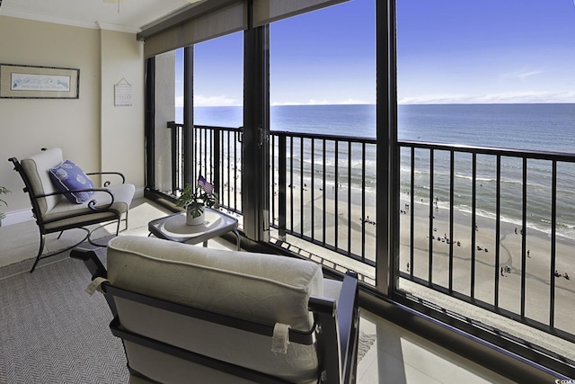 living room with a view of the beach, a water view, and ornamental molding