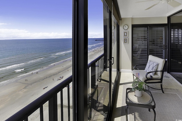 balcony with ceiling fan, a water view, and a view of the beach