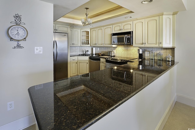 kitchen featuring sink, a raised ceiling, kitchen peninsula, decorative backsplash, and appliances with stainless steel finishes