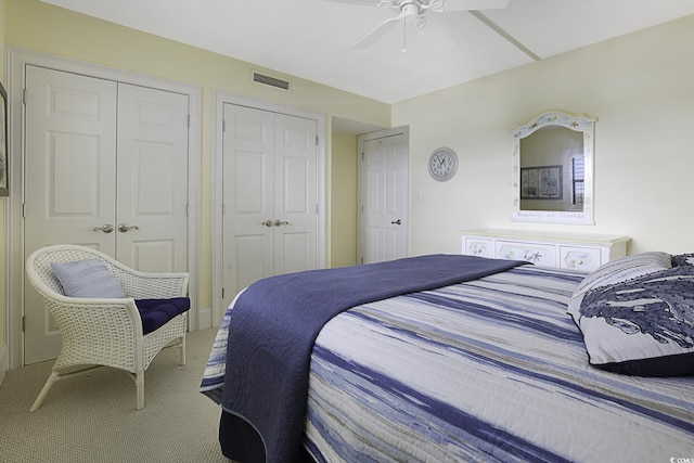 bedroom with carpet floors, two closets, and ceiling fan