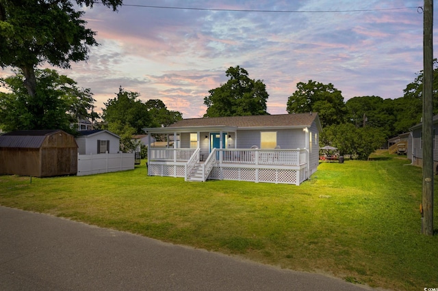 view of front of house with a yard, a shed, and a deck