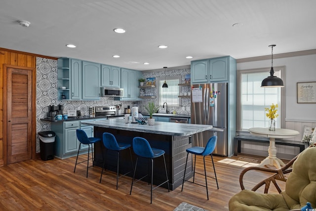 kitchen featuring ornamental molding, appliances with stainless steel finishes, dark hardwood / wood-style flooring, and a center island