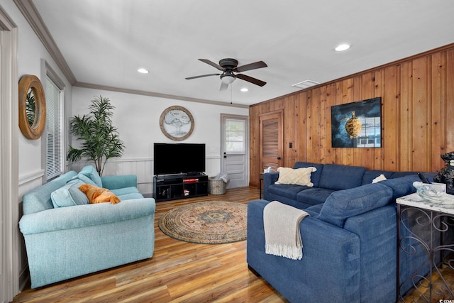 living room with wood walls, ceiling fan, ornamental molding, and hardwood / wood-style flooring