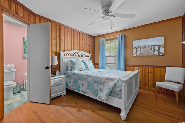 bedroom with wood walls, ceiling fan, ornamental molding, and hardwood / wood-style floors