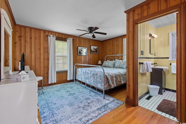 bedroom featuring ornamental molding, ceiling fan, wood walls, and wood-type flooring