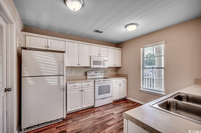 kitchen with sink, white cabinets, hardwood / wood-style flooring, and white appliances