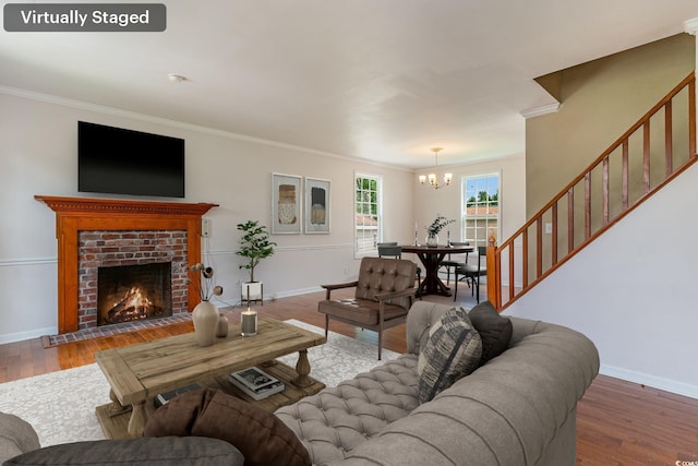 living room featuring ornamental molding, a fireplace, a chandelier, and hardwood / wood-style floors